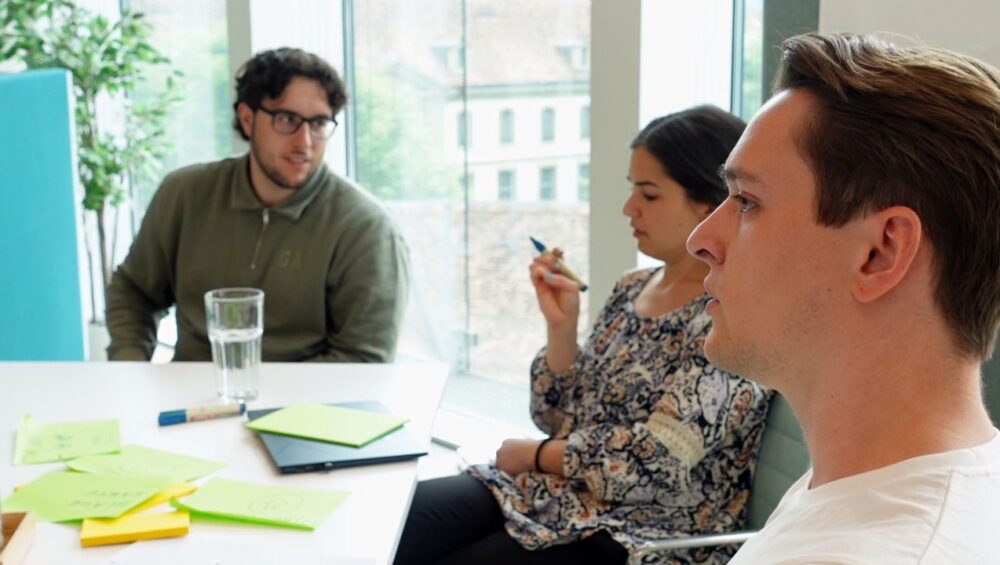 Das Team von Epic Fusion gemeinsam an einem Arbeitstisch im Coworking Space zentroom