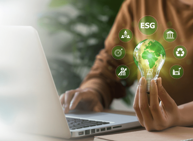 Person hält eine Glühbirne am Laptop, umgeben von Icons zu Nachhaltigkeit, Umwelt und Energieeffizienz.